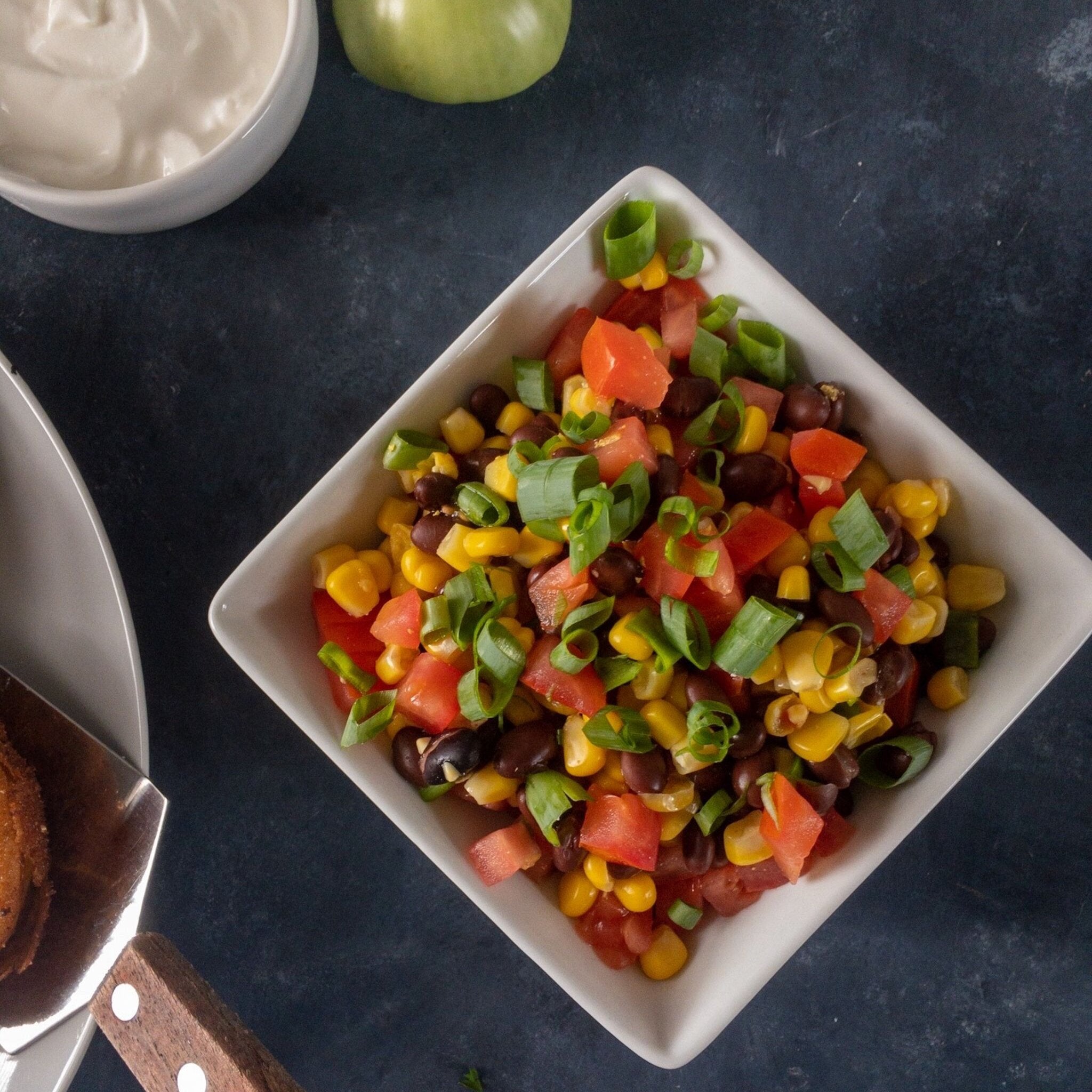 black bean corn salsa in white square bowl